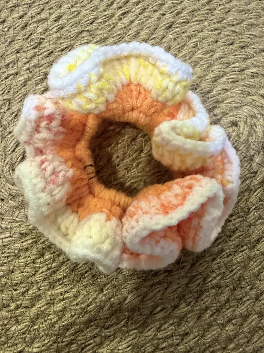 A handmade ruffle scrunchie in peach-orange and cream.
