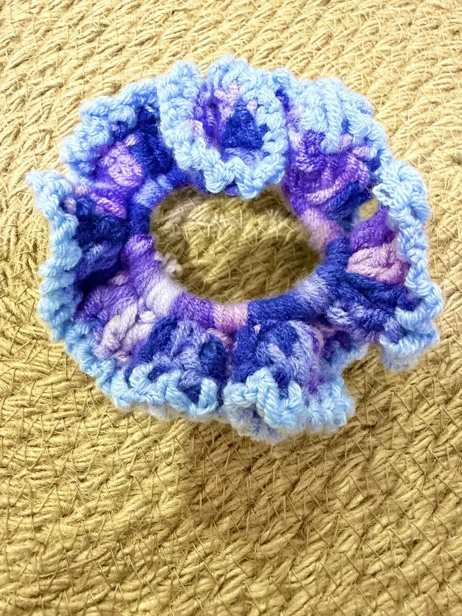 A handmade ruffle scrunchie in variegated blue and purple with a light blue edge.