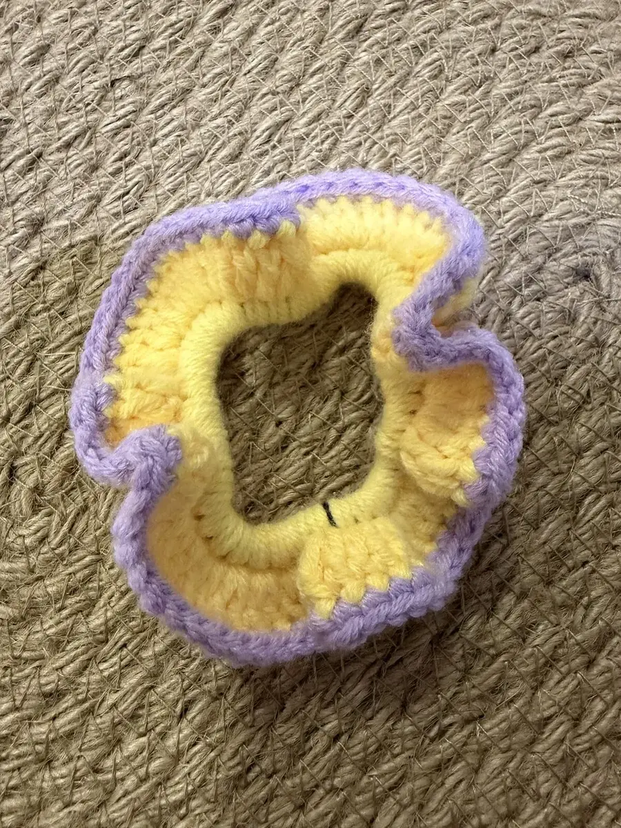 A handmade ruffle scrunchie in yellow with a lilac edge.