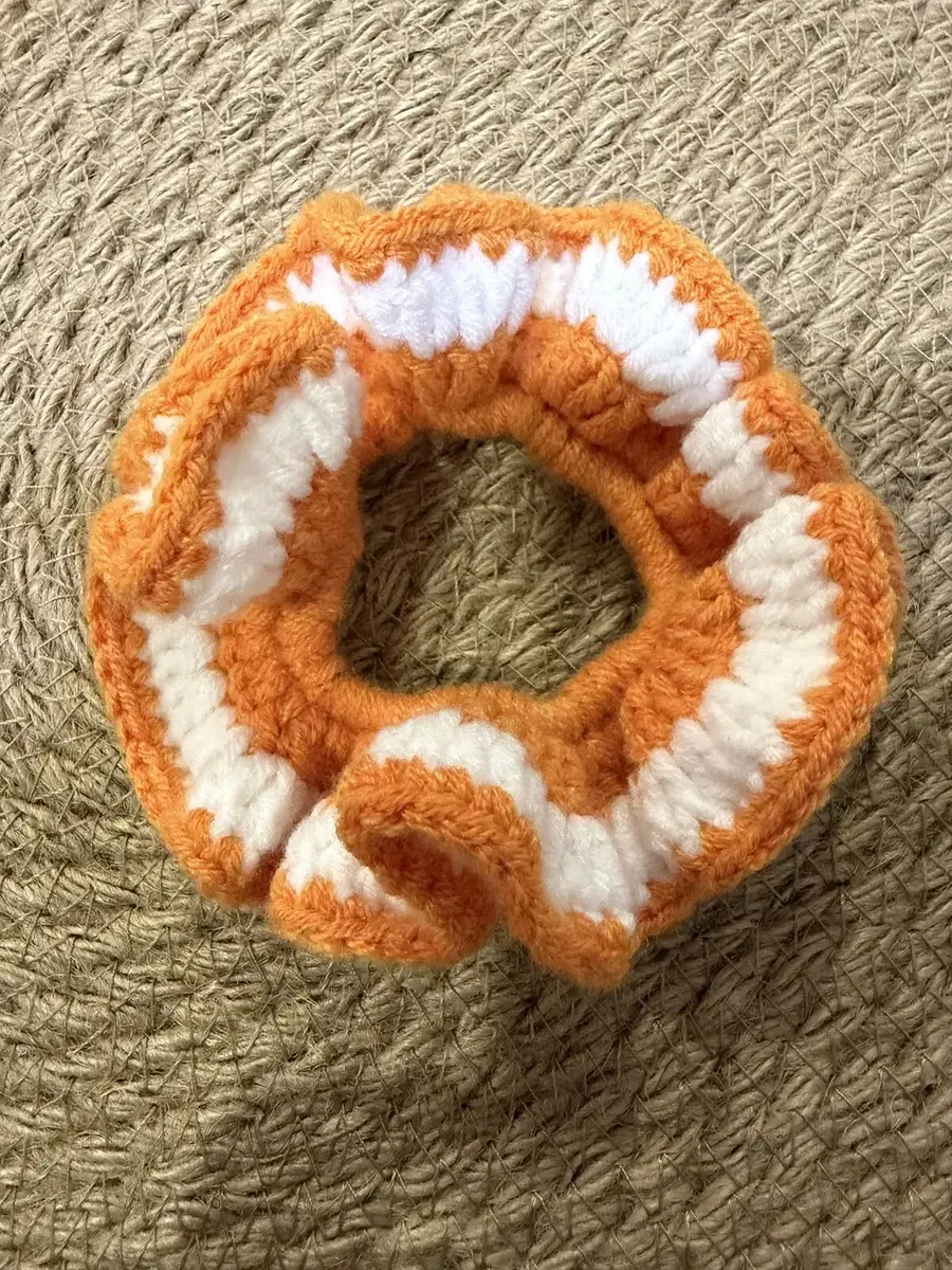 A handmade ruffle scrunchie in orange with white stripes.