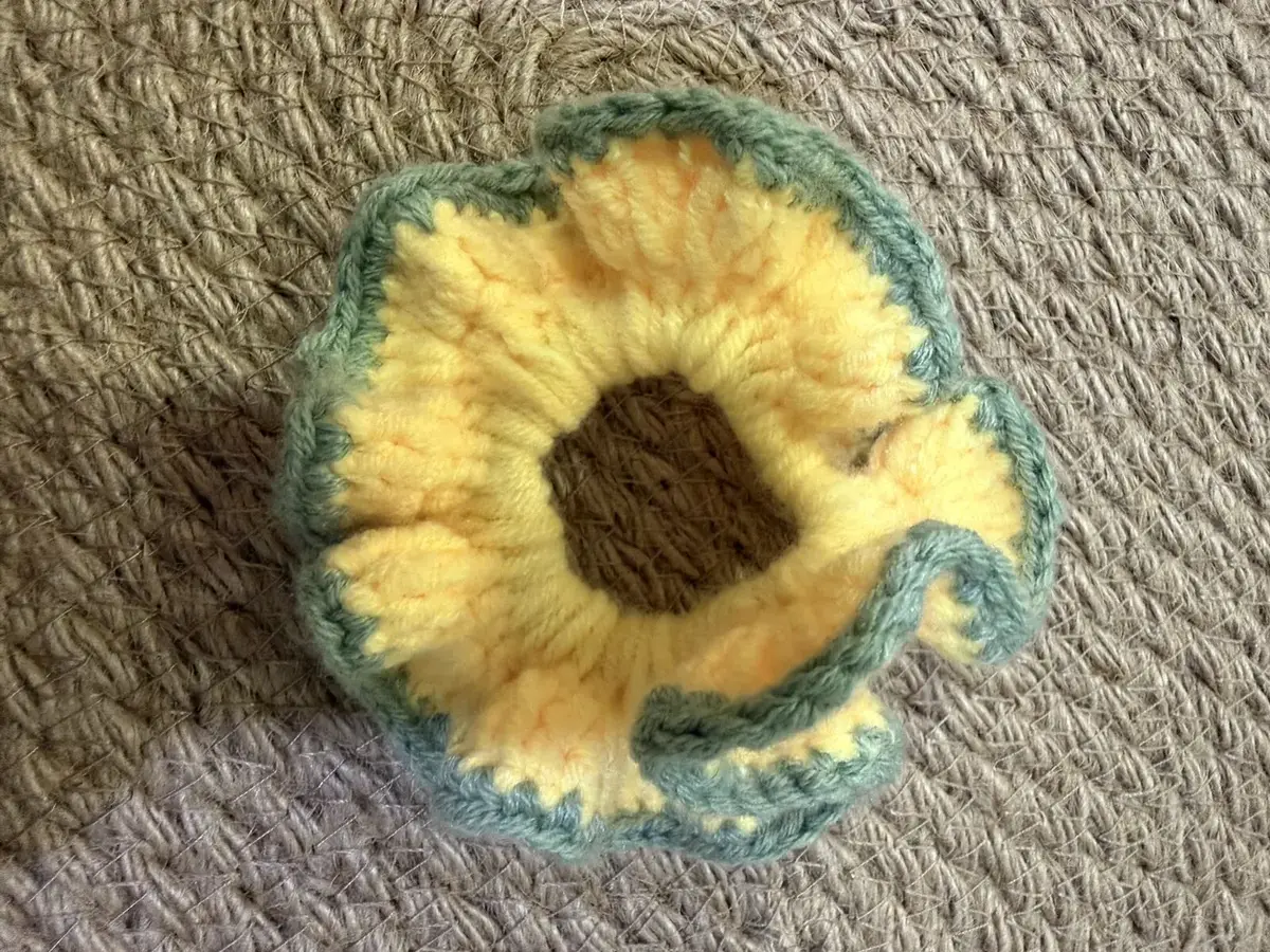 A handmade ruffle scrunchie in yellow with a sage-green edge.