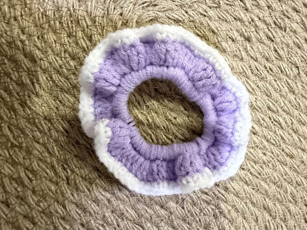 A handmade ruffle scrunchie in lilac with a white edge.