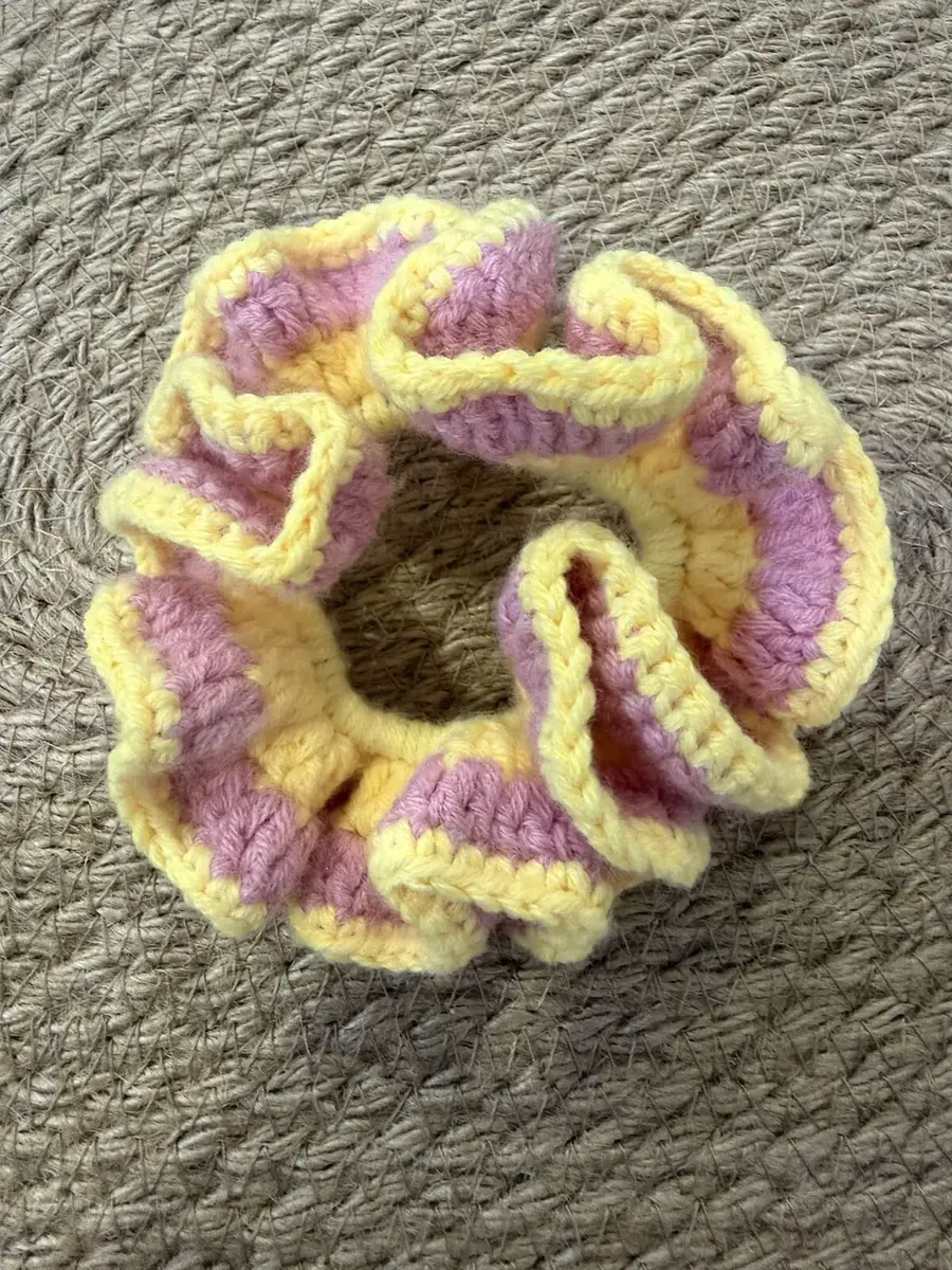 A handmade ruffle scrunchie in pink with a yellow edge.