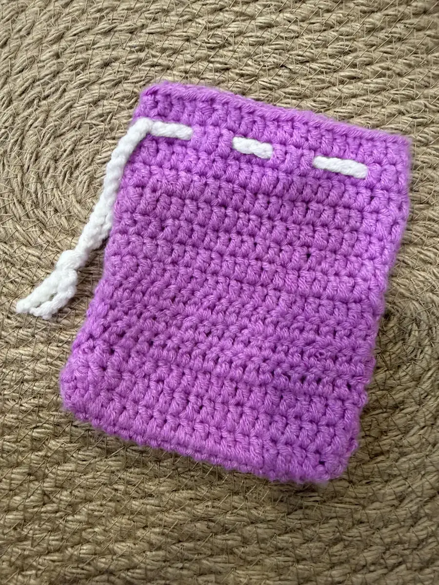 A crochet drawstring pouch in magenta and purple.