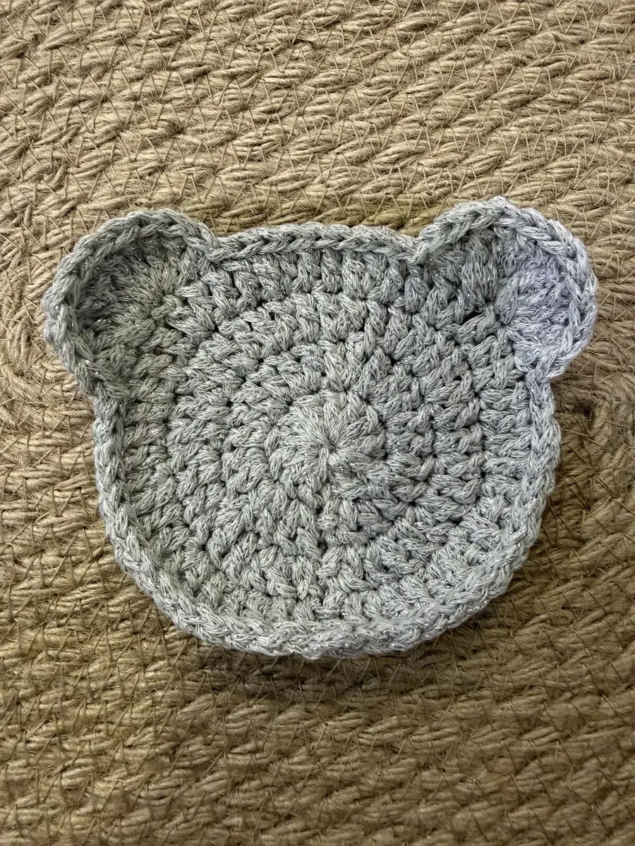 A grey and silver bear-head coaster.