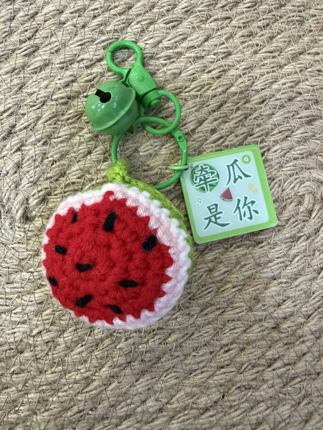 A crochet watermelon keychain with a green top.