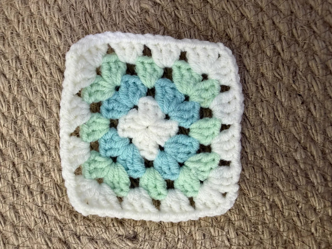 A crochet granny square in mint and white.